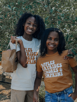 Two kids wearing shirts that say Apples, Hayrides, S'mores, and Pumpkins.