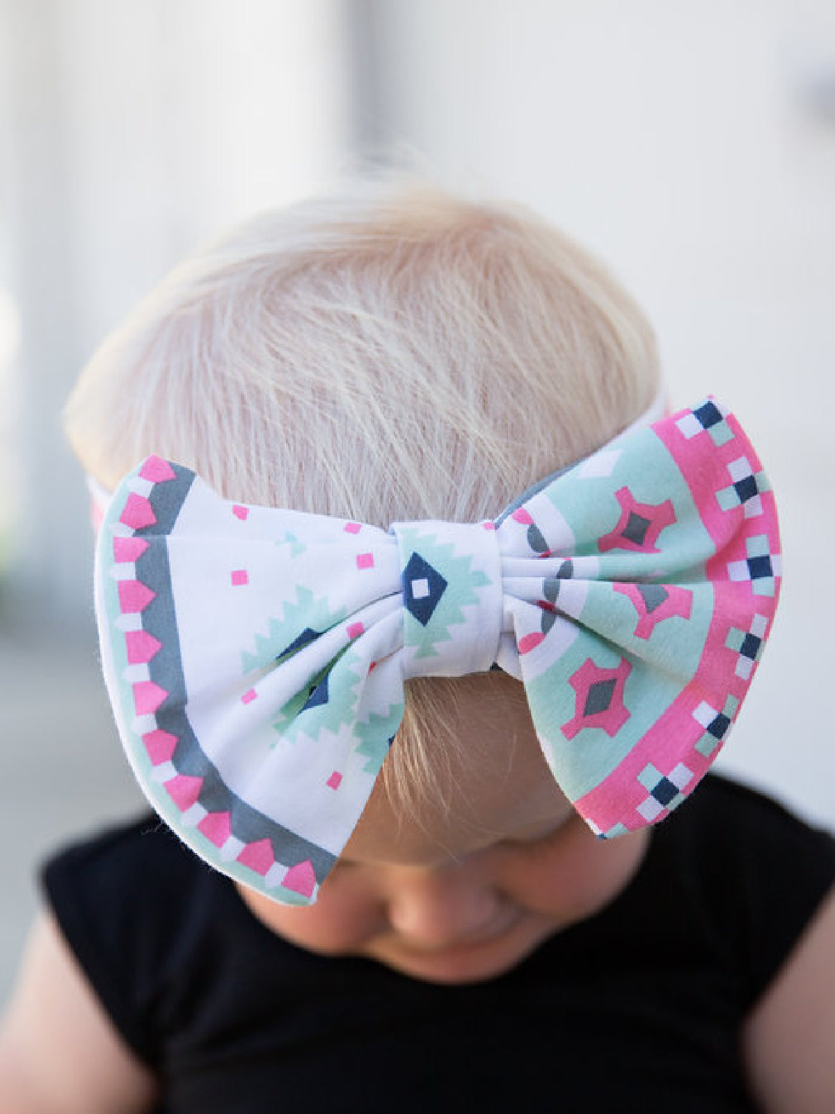 Mommy and me matching headband set with pastel Aztec print; adult twisted knot and child bow style on a white background.