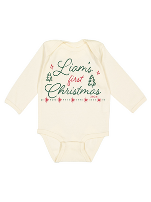 An off-white long-sleeve baby bodysuit with a festive Christmas graphic on the front reading 'Liam's first Christmas 2023' in green and red lettering with small tree and star illustrations.