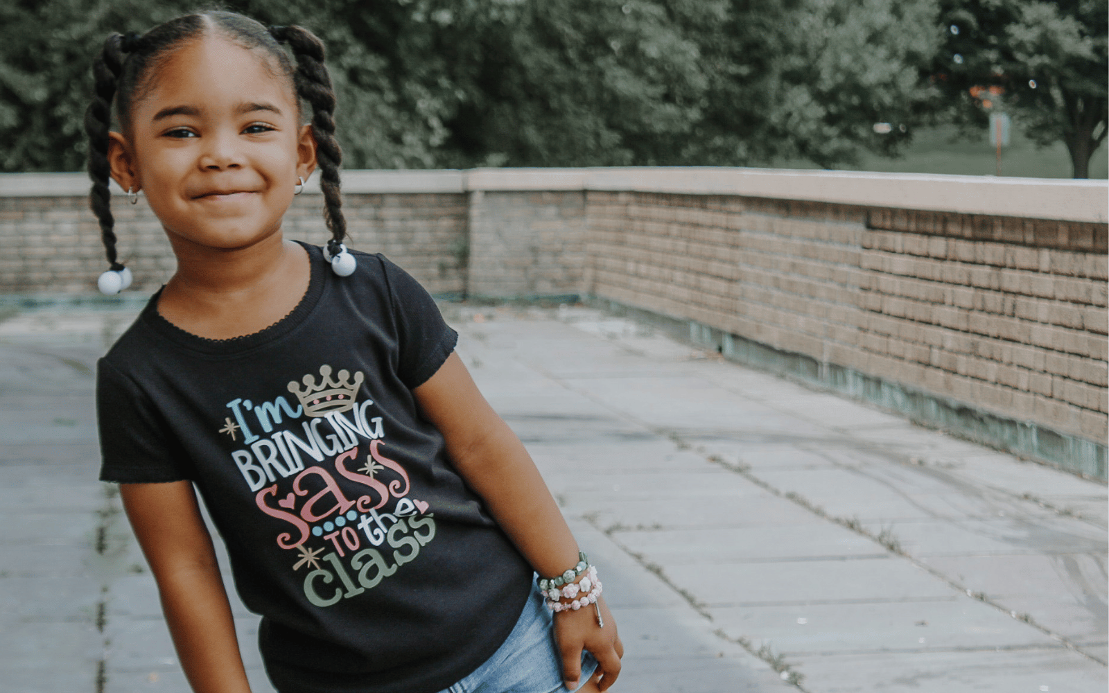 Young girl wearing shirt that says 'I'm Bringing Sass to the Class'