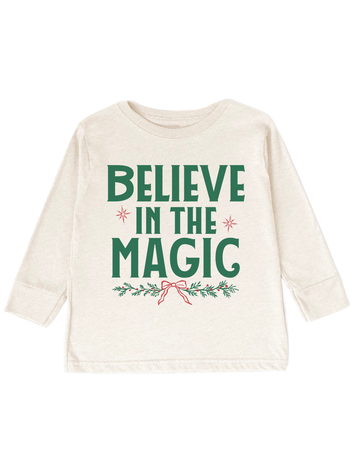 An off-white long-sleeve baby t-shirt with a festive graphic that reads 'BELIEVE IN THE MAGIC' in green, decorated with small red stars and a red bow on a green holly branch, shown on a plain white background.