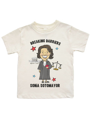 Cream-colored kids' Women's History Month shirt featuring an illustrated Sonia Sotomayor with "Breaking Barriers" text and legal icons.