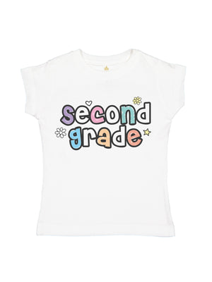 A white short-sleeve kids' t-shirt featuring a colorful graphic that reads 'second grade' in pastel bubble letters with small decorative doodles, shown against a plain white background.