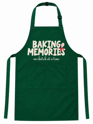 A dark green apron with a front pocket, featuring the text 'BAKING MEMORIES' in white with a small red and white whisk graphic, and the phrase 'one batch at a time' underneath.