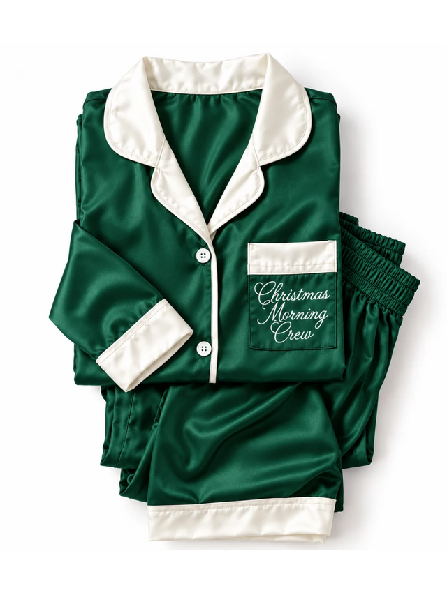 Folded green pajamas with cream cuffs with pocket reading Christmas Morning Crew in script
