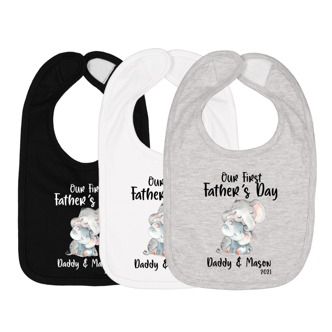 Three baby bibs in black, white, and gray with elephant graphic and text “Our First Father’s Day