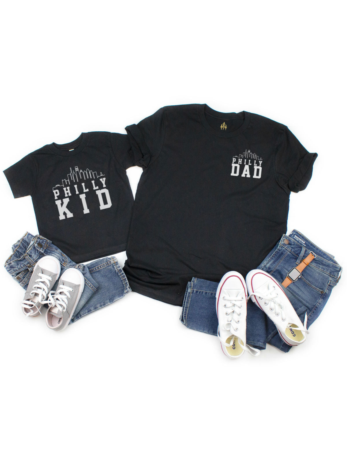 Flat lay of matching Philly Dad and Philly Kid black t-shirts with jeans and sneakers