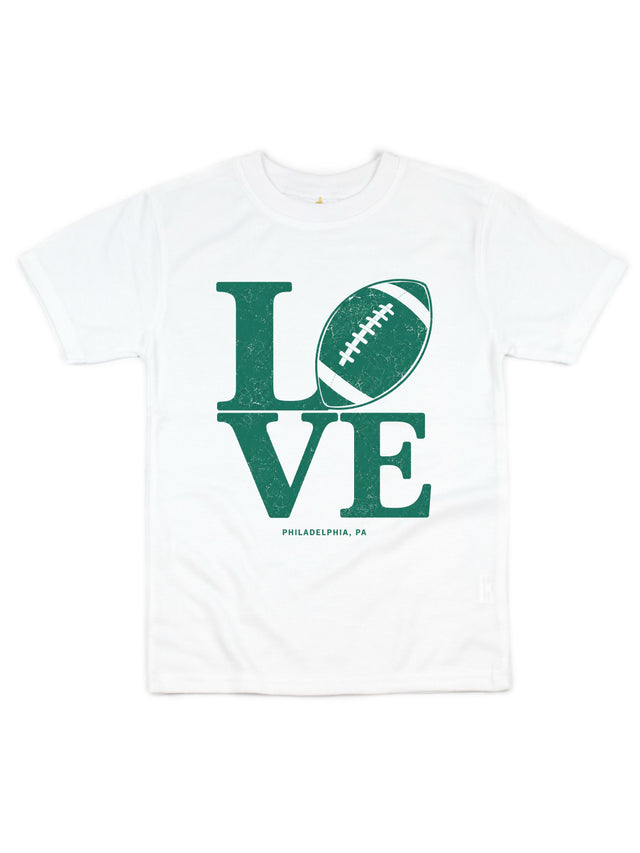 A white short-sleeve crewneck t-shirt featuring a distressed green graphic that spells 'LOVE' with a football representing the letter 'O', and 'PHILADELPHIA, PA' printed below.