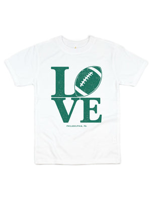 A white short-sleeve crewneck t-shirt featuring a distressed green graphic that spells 'LOVE' with a football representing the letter 'O', and 'PHILADELPHIA, PA' printed below.