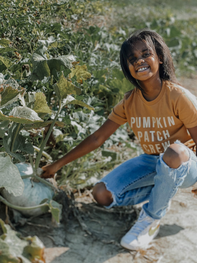 Child wearing Pumpkin Patch Crew shirt at the pumpkin patch – fall outfit idea for toddlers and kids