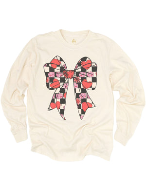 Natural-colored Coquette Valentine Bow shirt featuring a retro bow design with checkered hearts, pink dice, and flowers, displayed flat on a white background.