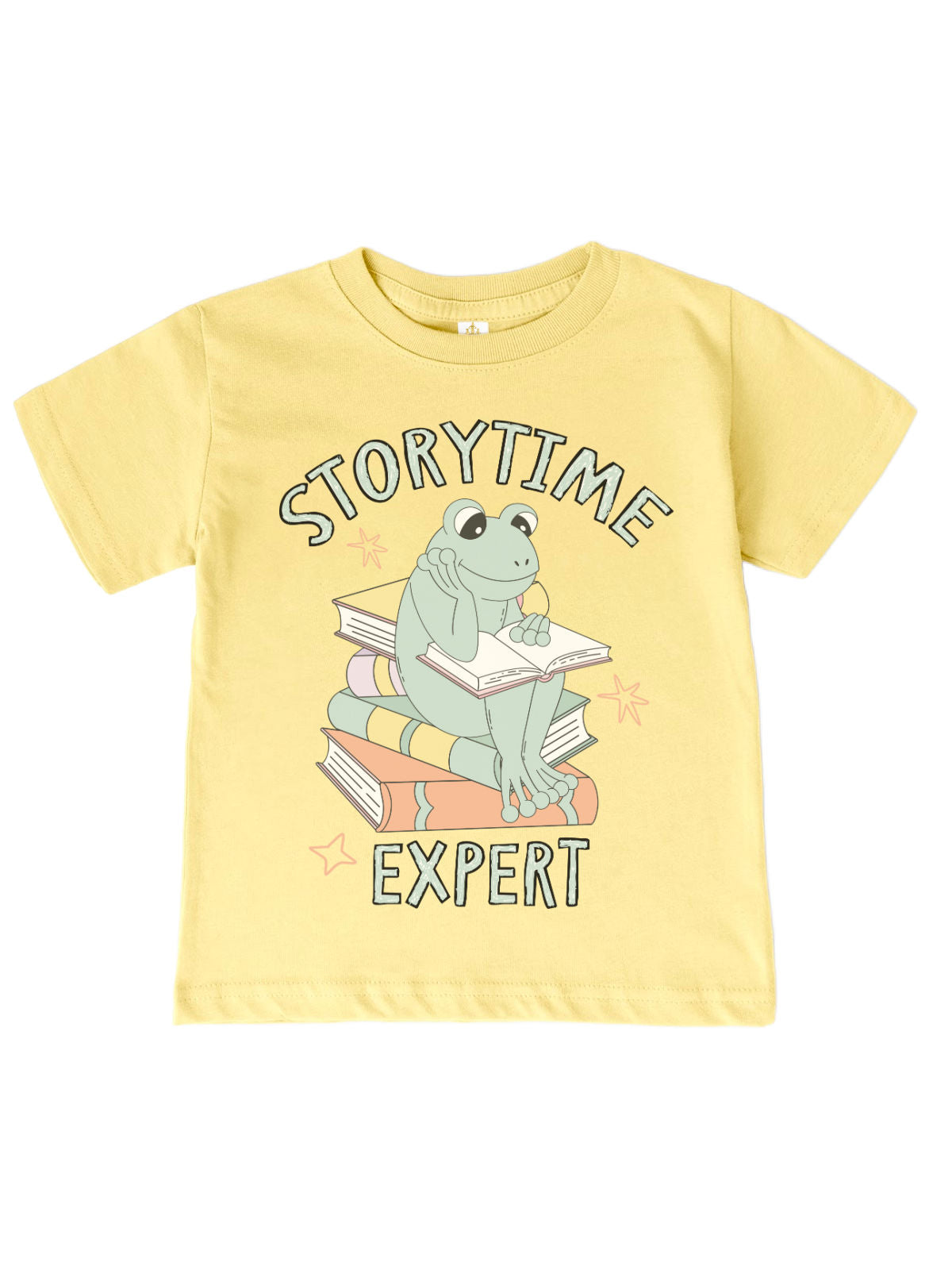 Kids' spring shirt in banana yellow featuring a cute reading frog sitting on a stack of books with "Storytime Expert" text. Soft 100% cotton, unisex fit.