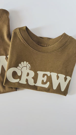 Video showing three folded brown short sleeve shirts with Thanksgiving Crew in retro style font