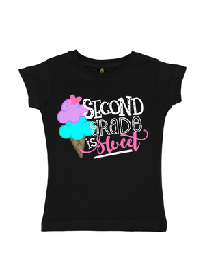 A black short-sleeve t-shirt for girls, featuring a colorful graphic on the front with an ice cream cone and the text 'SECOND GRADE is sweet' in white, pink, and turquoise lettering.