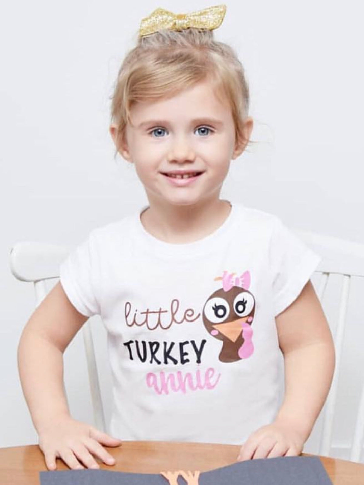 Young girl wearing white shirt that reads Little Turkey