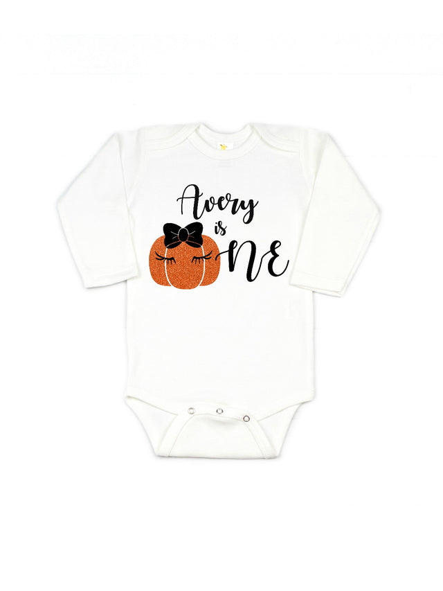 Personalized girls long sleeve bodysuit that reads "name is One" with pumpkin in a bow