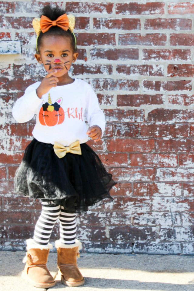 Little girl wearing long sleeve white shirt with unicorn pumpkin and personalized with the name Khloe.