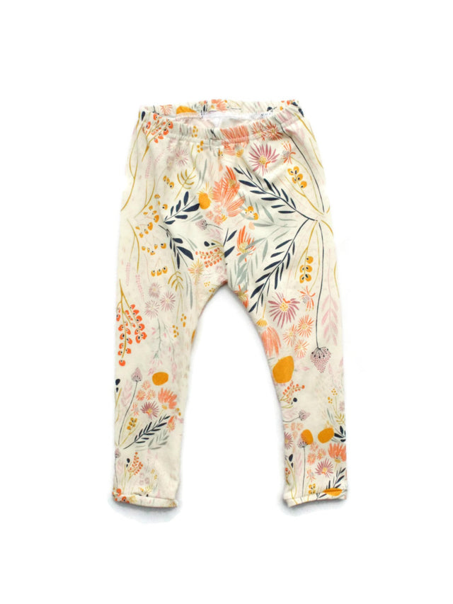 Kids floral leggings with whimsical wildflowers and leaves in peach, mustard, lavender, and navy on a cream background